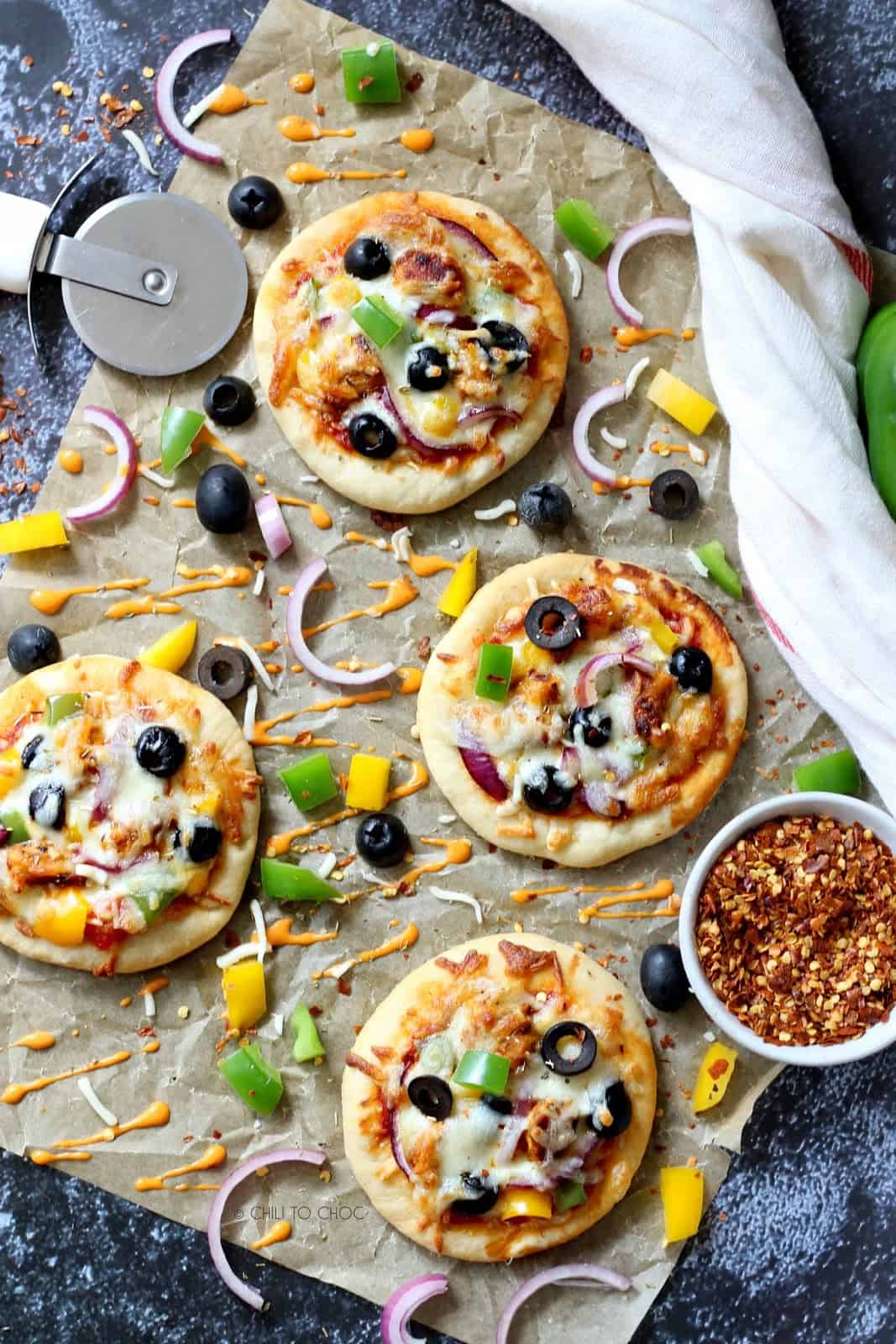 Overhead shot of mini pizzas on a parchment paper.