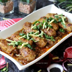 Seekh Kabab Masala on a white dish garnished with ginger slices, fresh coriander and green chilies