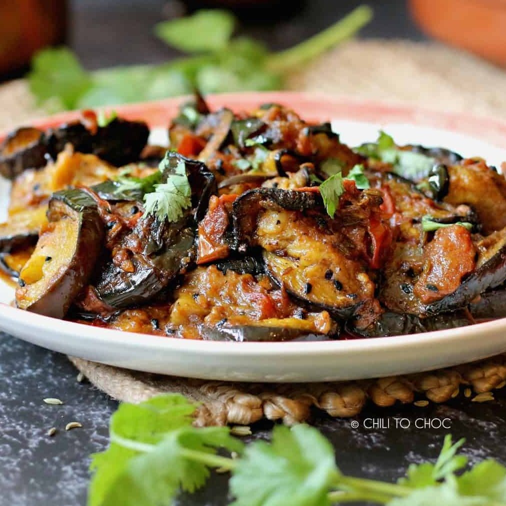 Achari baingan on a plate garnished with chopped coriander