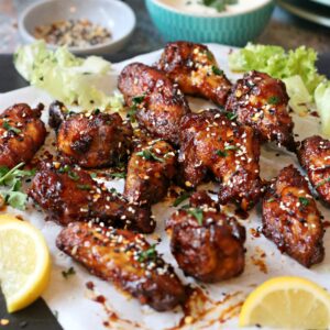 Sticky chicken wings garnished with sesame seeds with lemon wedges