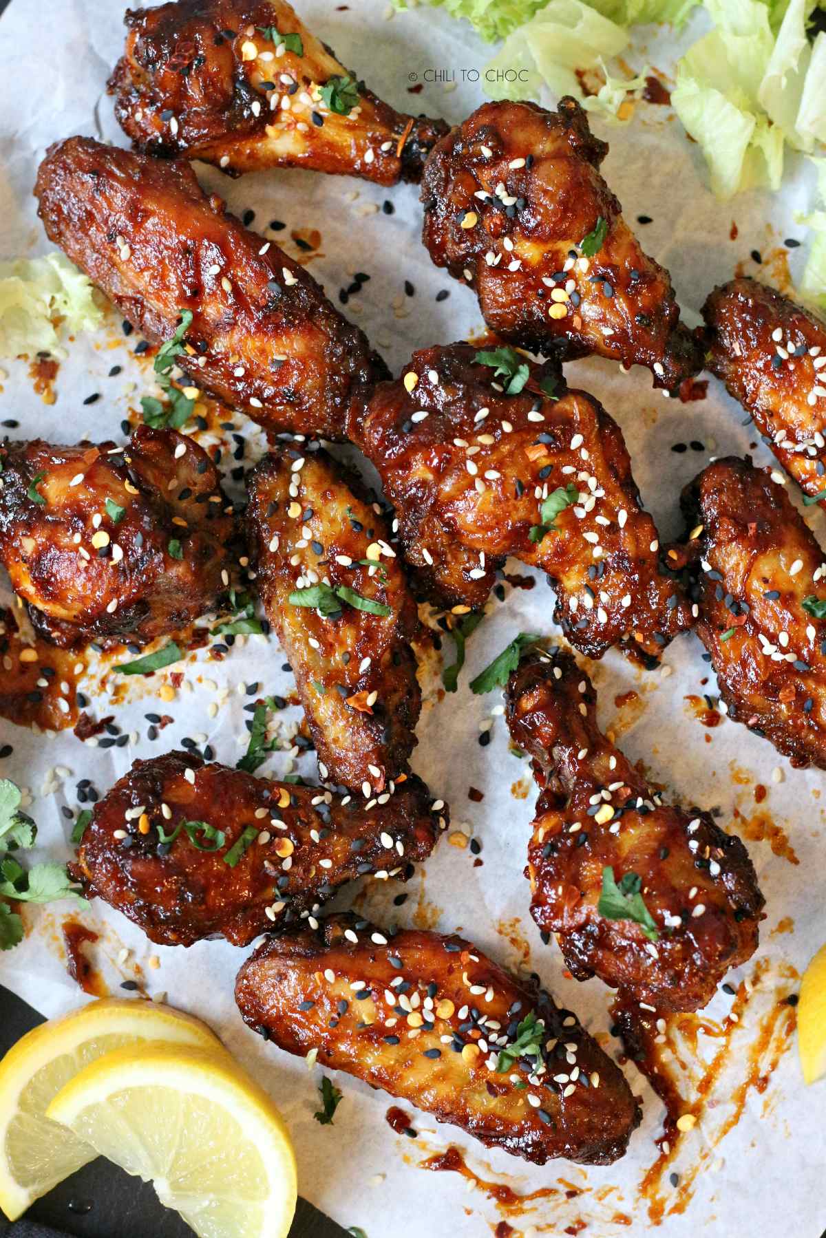 Overhead shot of baked Asian chicken wings on a white baking paper.