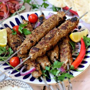 Turkish Adana Kebab on a dish with garnishes on top