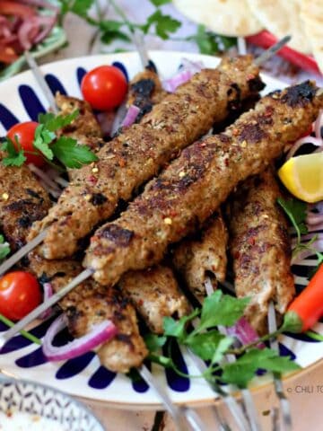 Turkish Adana Kebab on a dish with garnishes on top