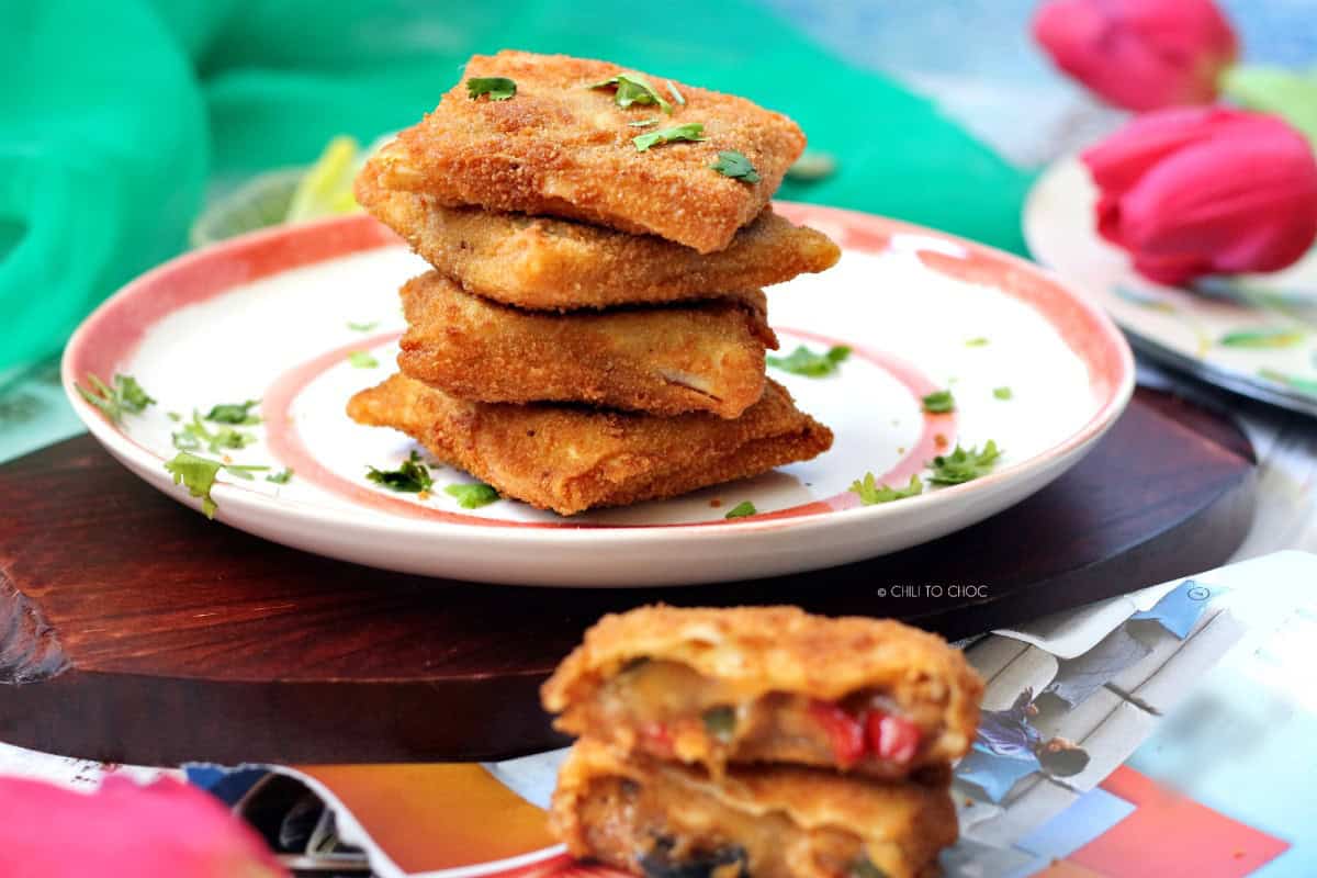 A plate of stacked box patties with one sliced open in the front, revealing the cheesy filling.