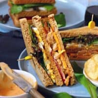 tandoori chicken club sandwich on a blue plate with a dip in front