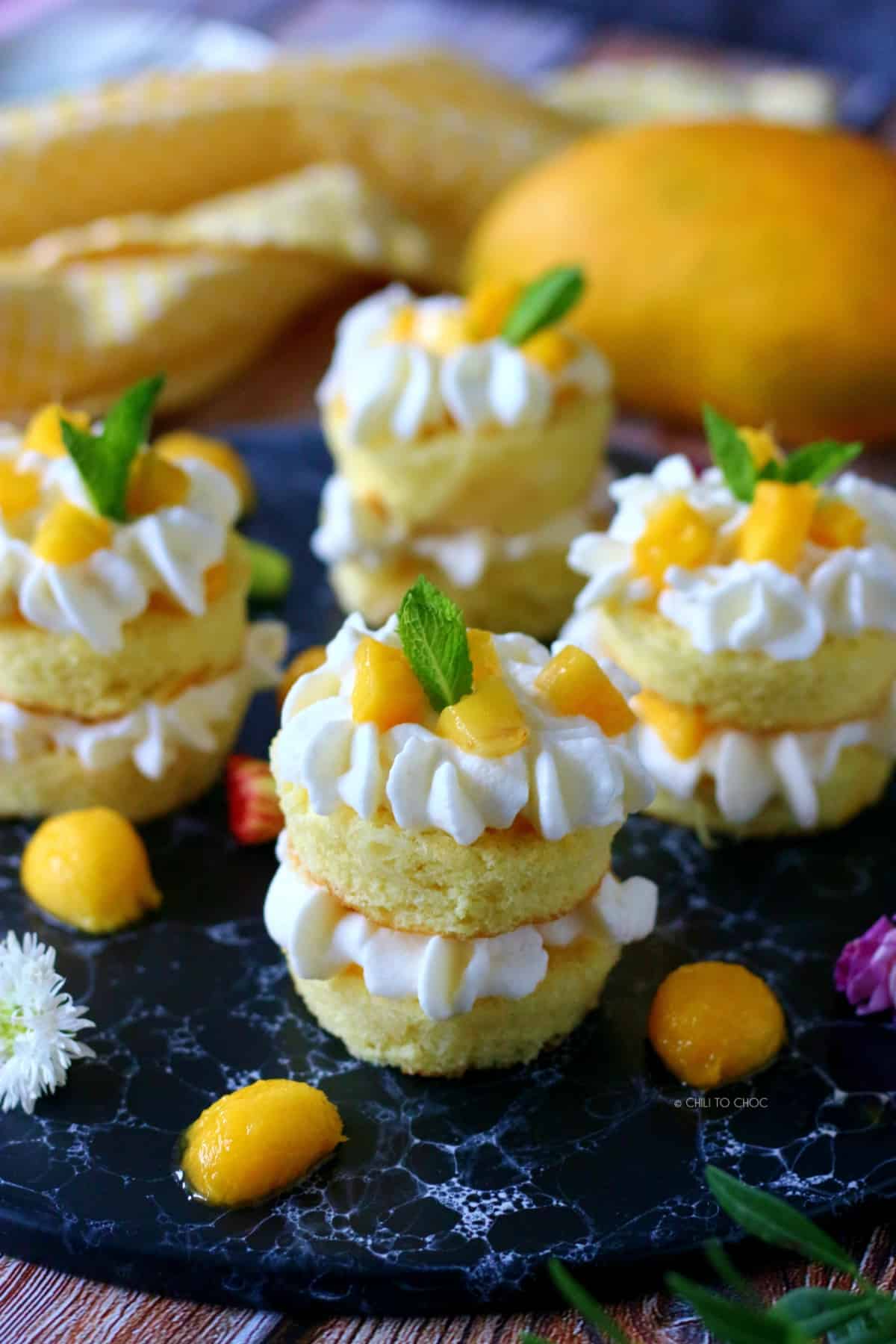 4 mini mango cakes with whipped cream frosting, mango chunks and mint