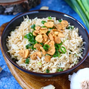 Garlic Butter Fried Rice in a shallow black dish topped with fried garlic slices and spring onion