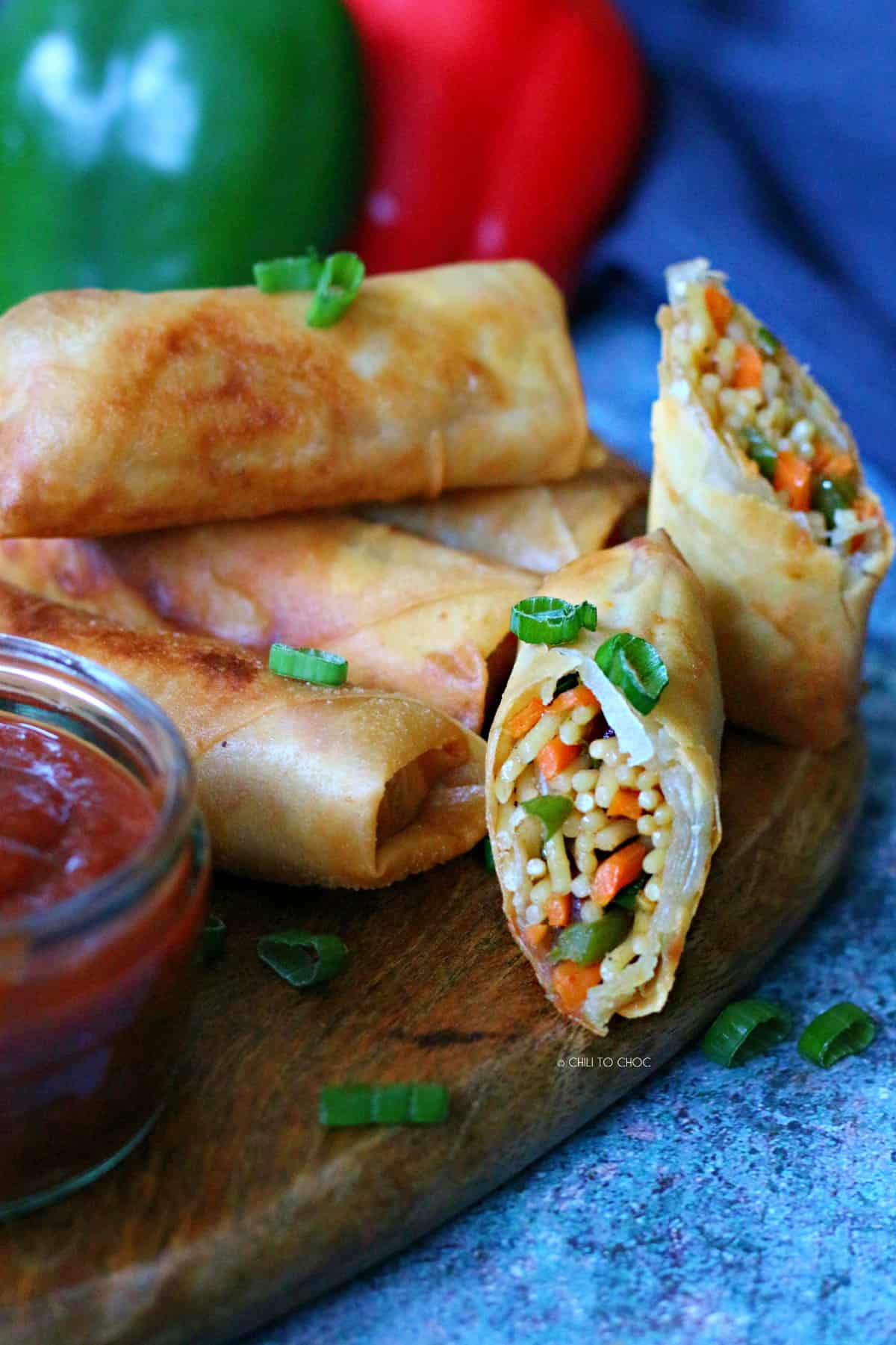 Vegetable and Noodle Spring Rolls on a brown tray with one of being halved from the center