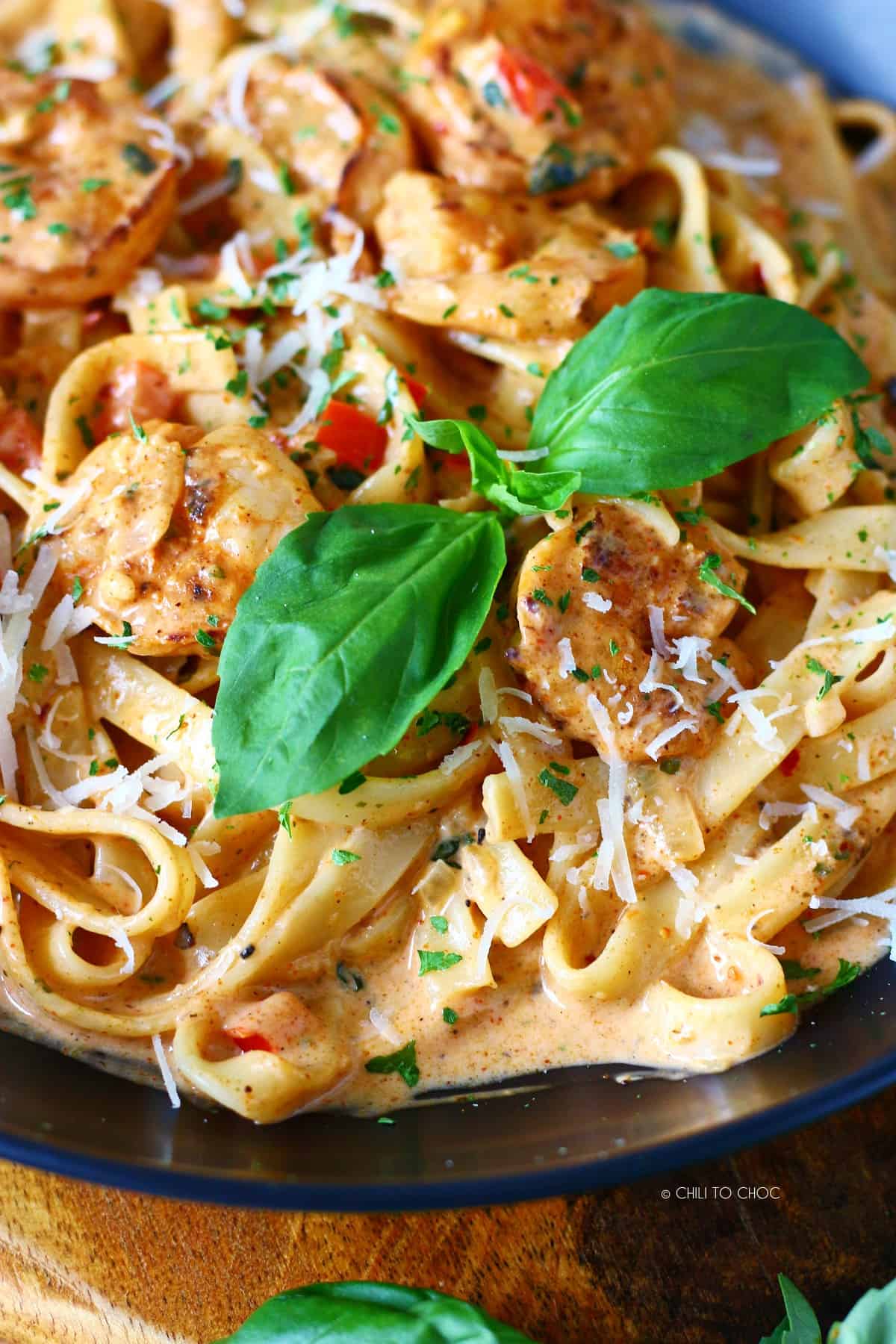 Close up of Cajun pasta with fresh basil leave and dried parsley.