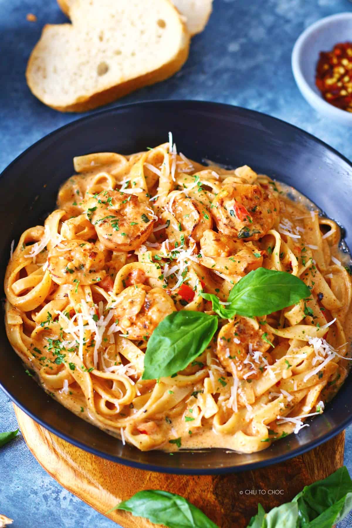 Creamy cajun shrimp pasta in a black plate topped with fresh basil.