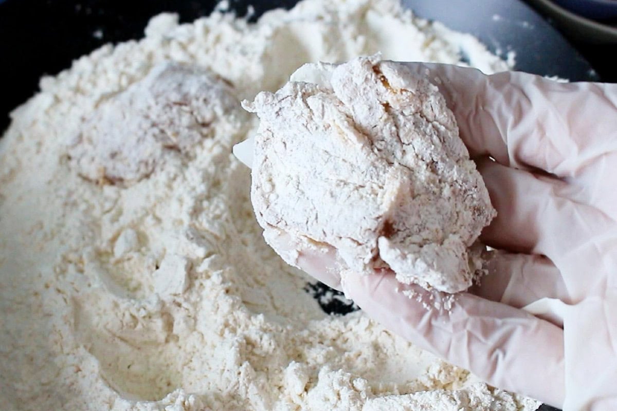 Coating the chicken with flour.