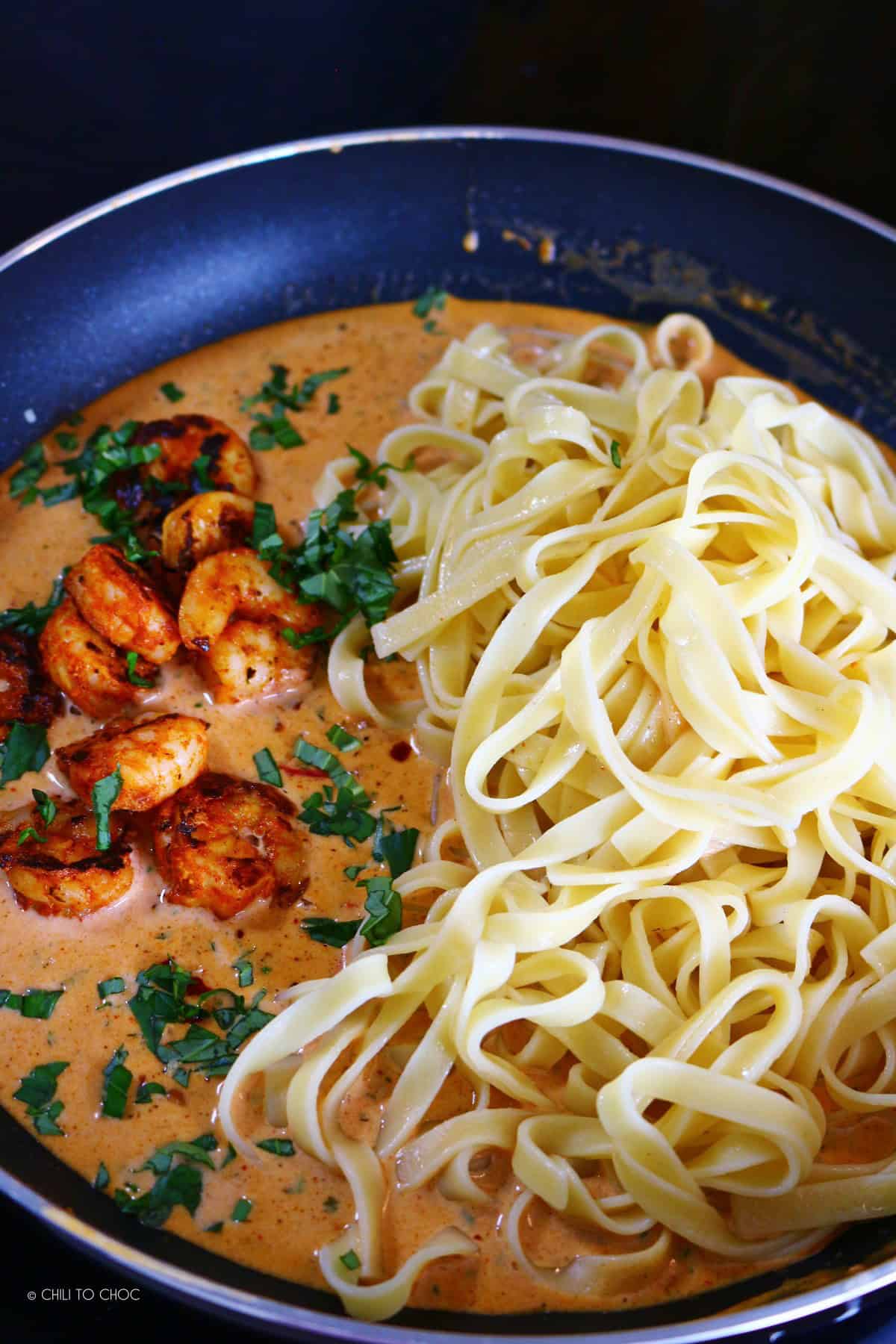 Cooked shrimp, boiled tagliatelle and creamy Cajun sauce in a pan.