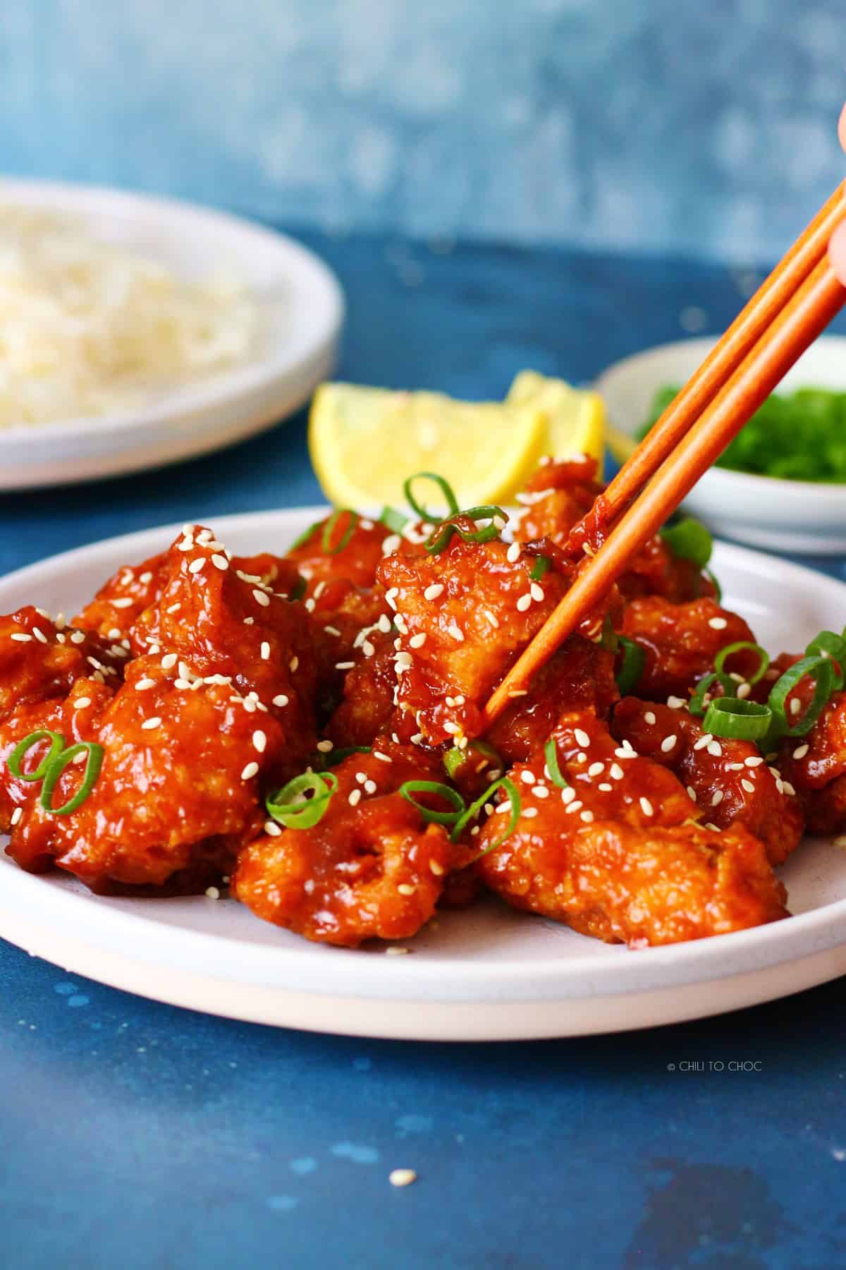 Picking a piece of honey sriracha chicken with a chopstick.