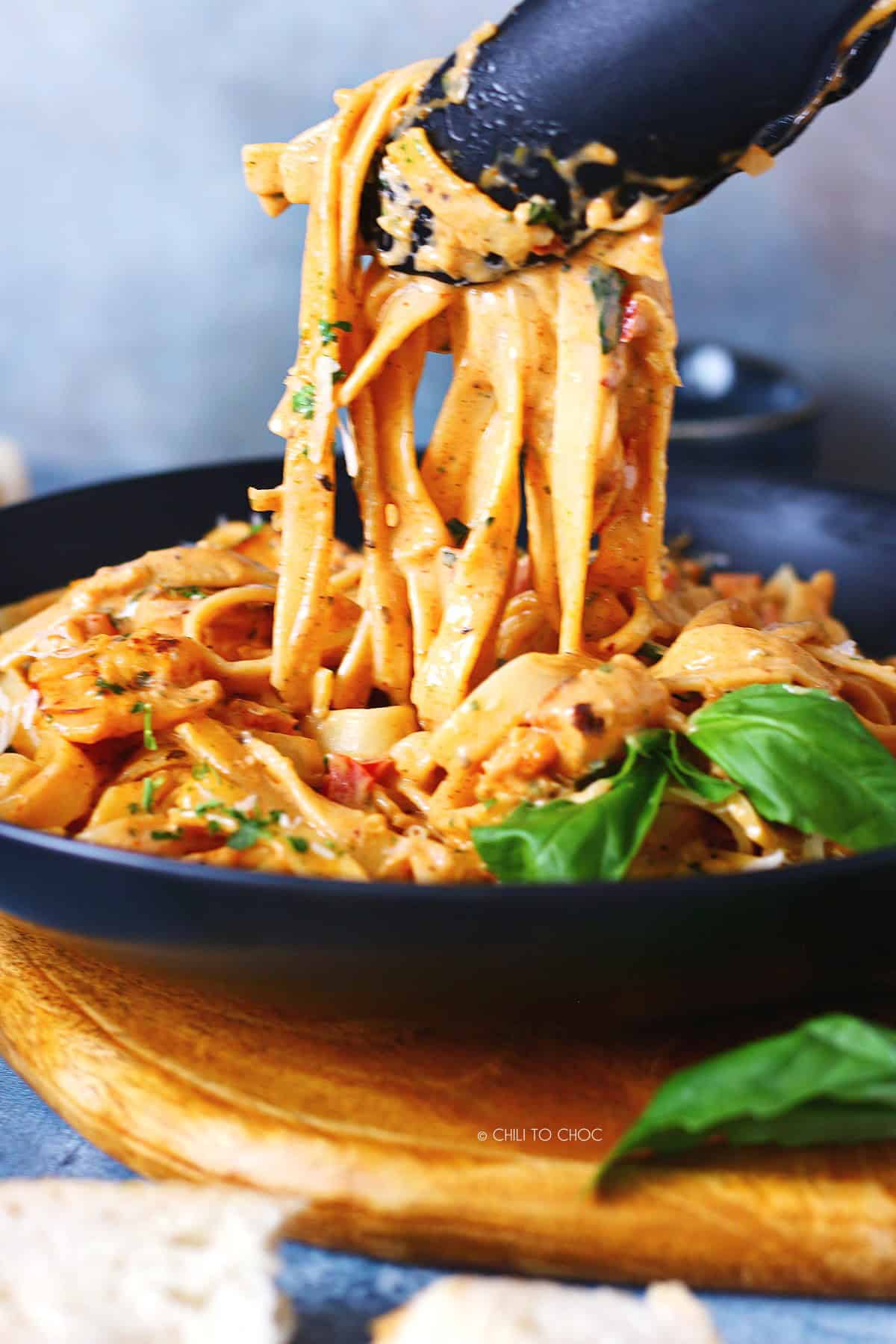 Picking the Cajun shrimp pasta from the plate with tongs.