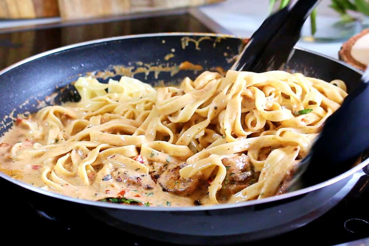 Tossing the pasta in the Cajun sauce.