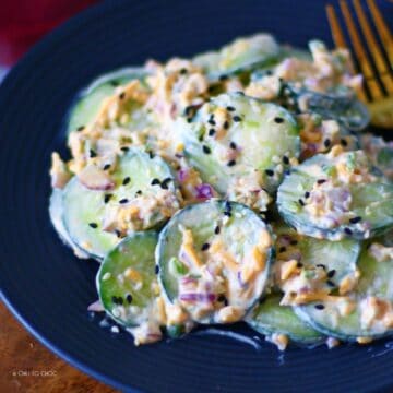 Jalapeno Popper Cucumber Salad on a black dish with a gold fork on the side.