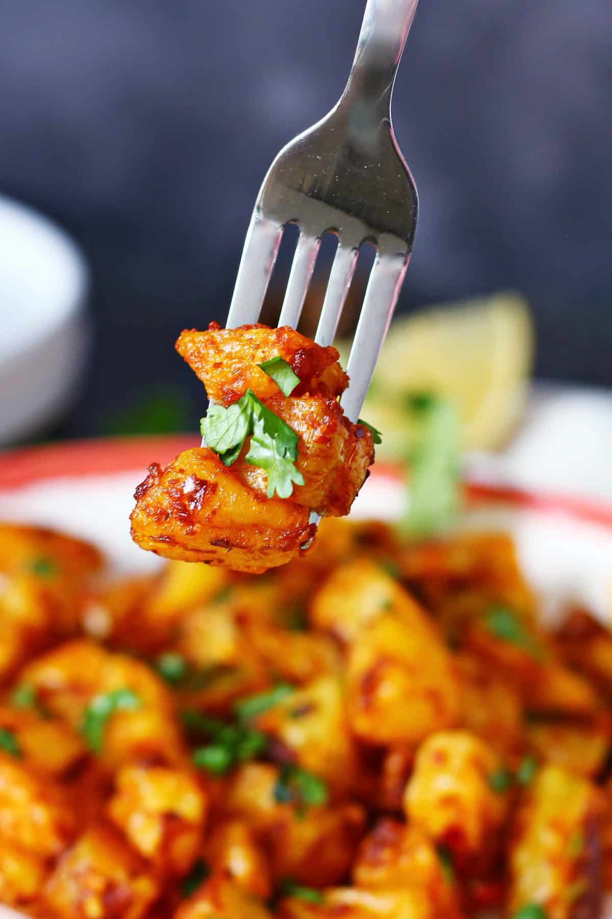 Three pieces of spicy potatoes on a fork.