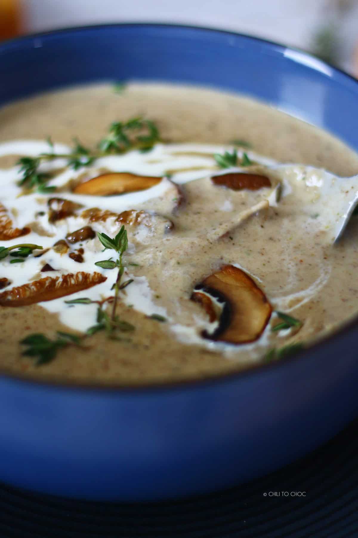 Mushroom soup with garnishes and spoon inside the bowl.