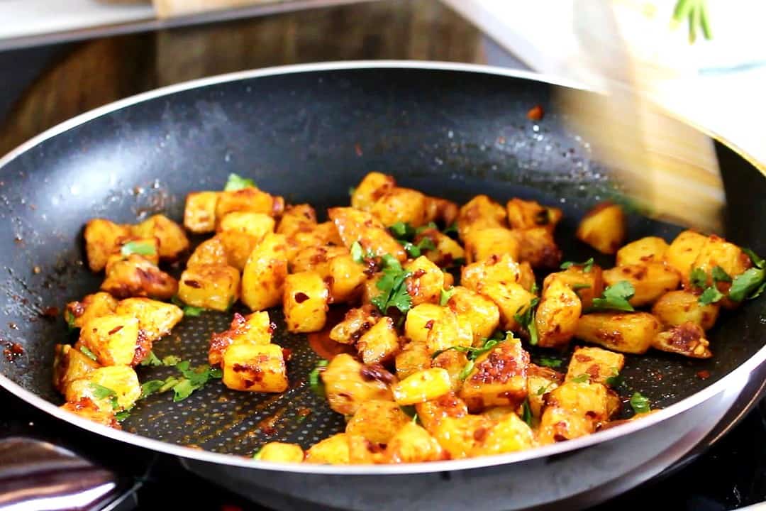 Tossed spicy potatoes in a pan.