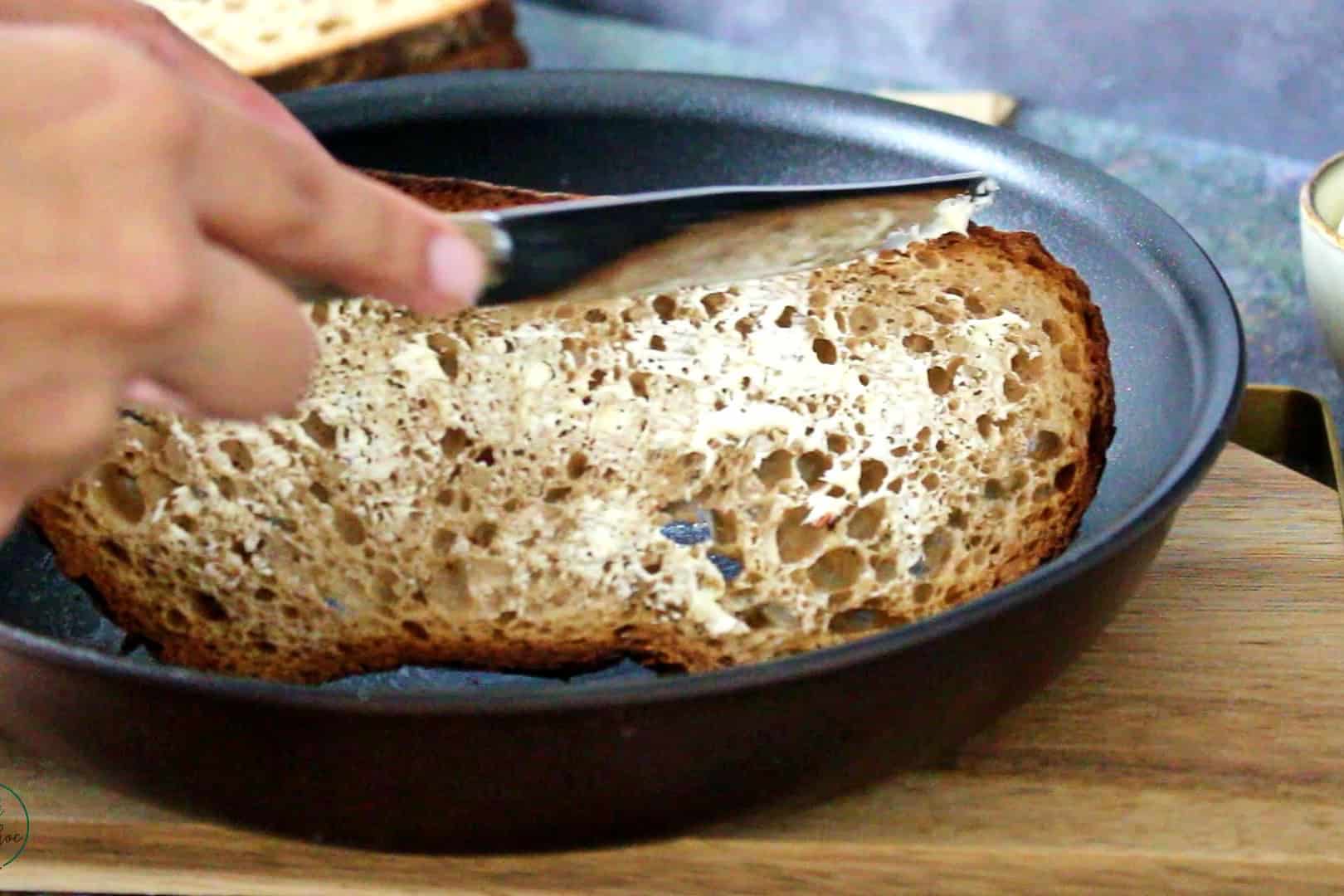 Smearing butter on sourdough bread.