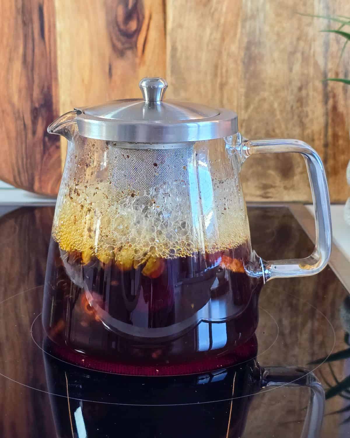 Black tea being brewed in a glass kettle.