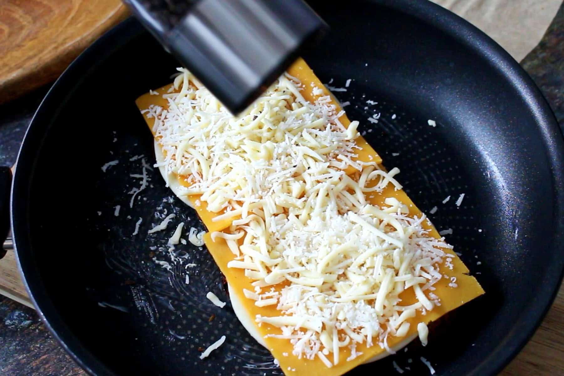 Adding black pepper to the cheese layers.