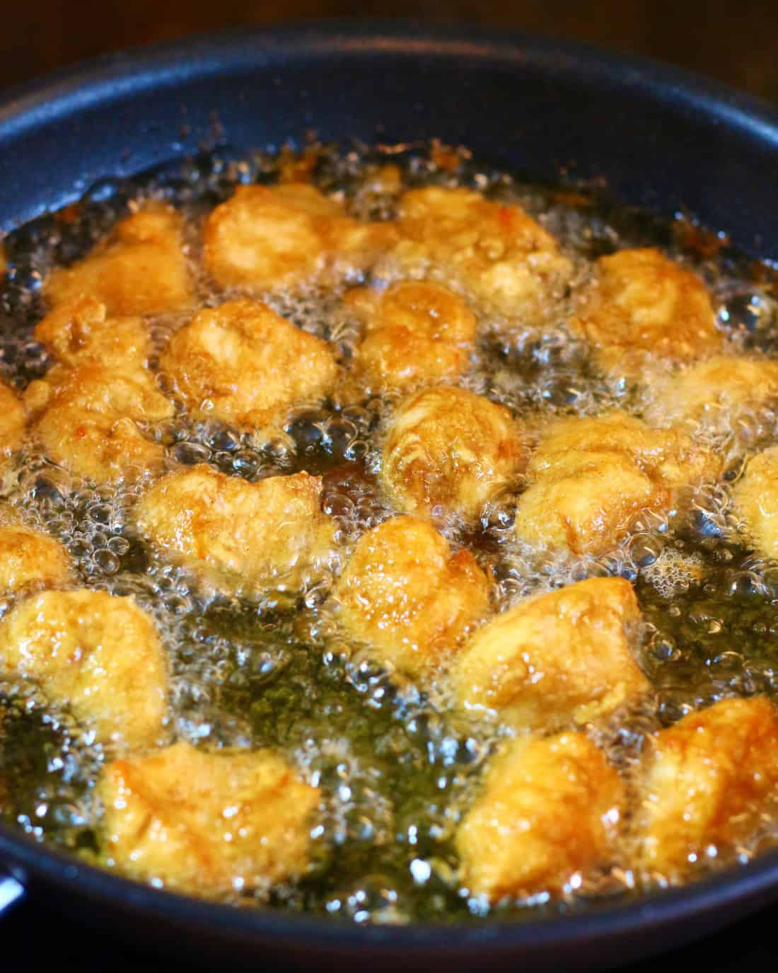 Fried chicken pieces in a pan with hot oil.