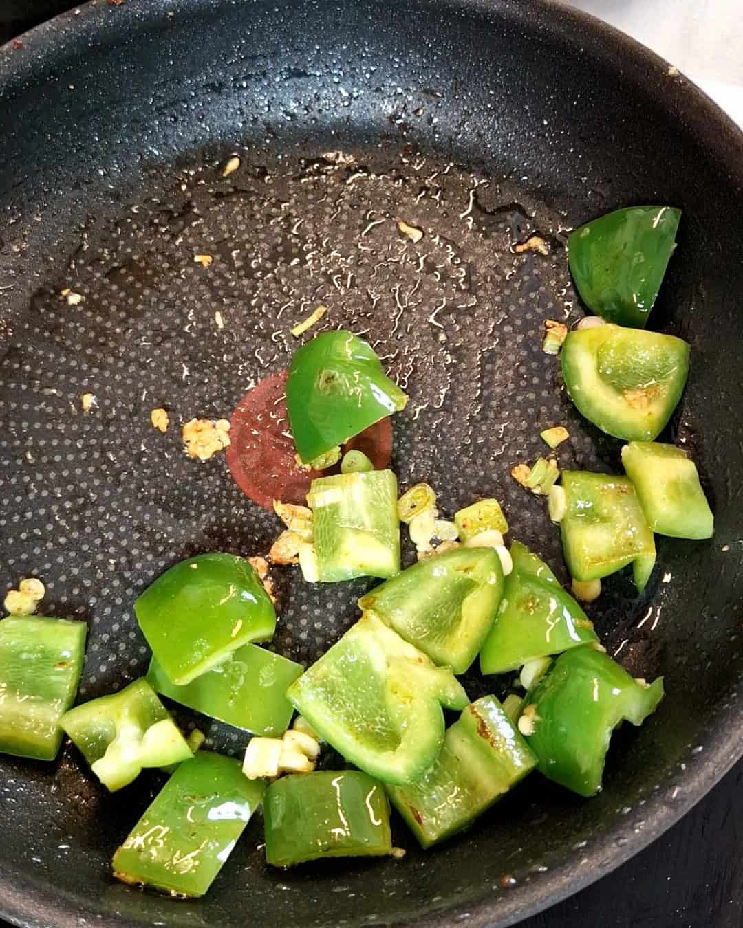 Cubed bell pepper in a black pan.