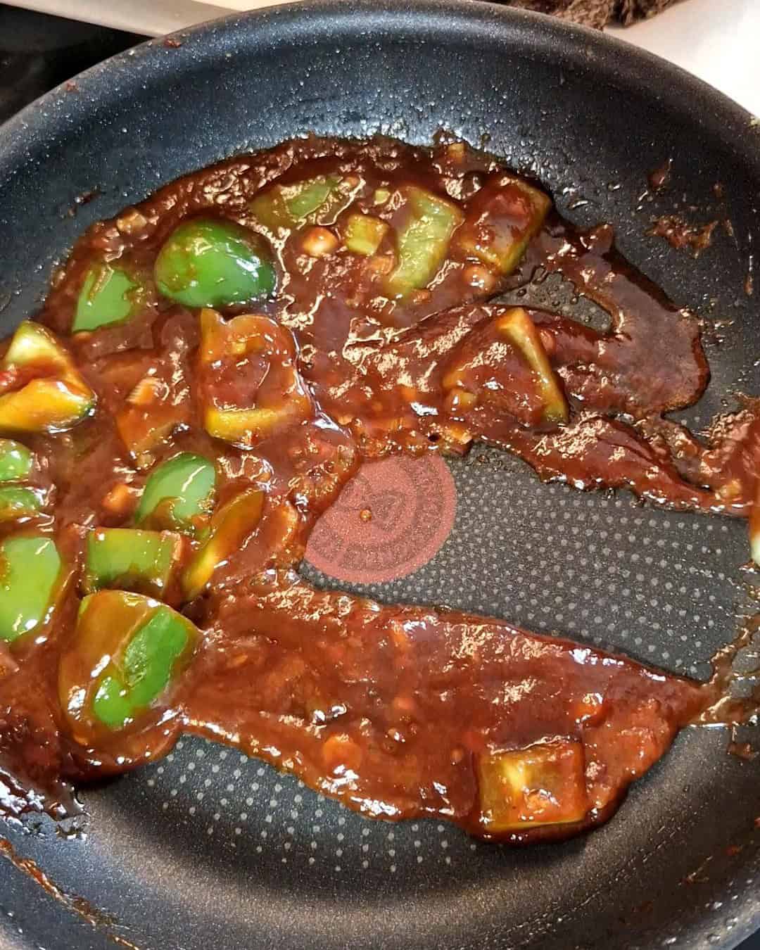 Bell pepper with red sauce in a black pan.