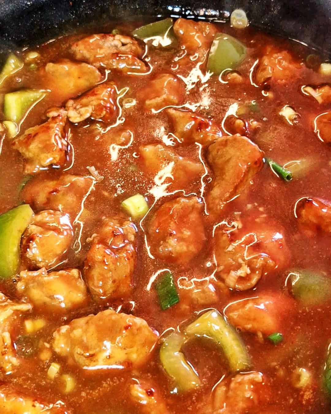 Fried chicken pieces mixed into the sauce with bell peppers and green onions.