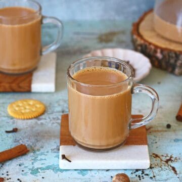 Two mugs of masala chai on coasters.