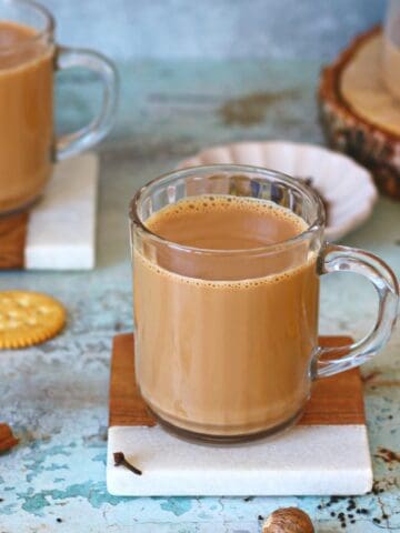 Two mugs of masala chai on coasters.