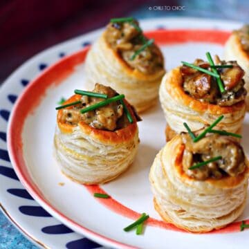 Group of chicken and mushroom vol au vent on a stack of plates.