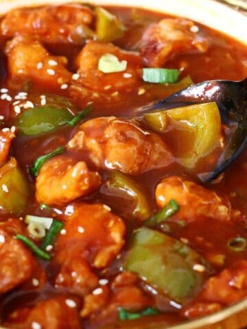 Serving spoon in Chicken Manchurian with bell peppers and sauce.