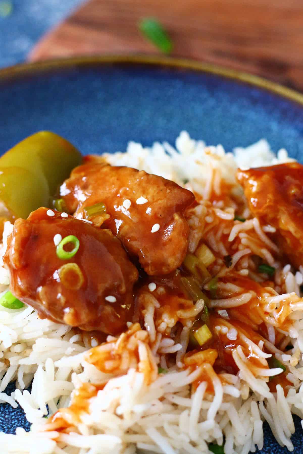 Chicken Manchurian served on top of steamed rice in a blue plate.