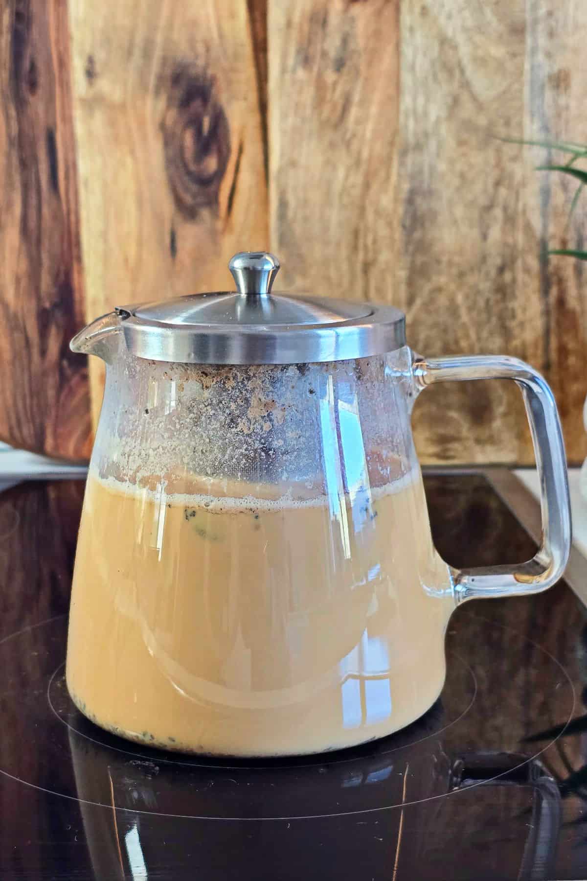 Milk tea on the stove inside a glass kettle.