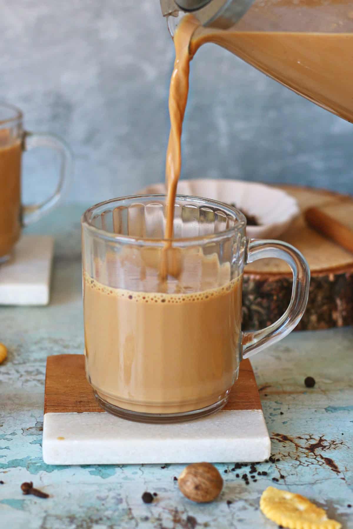 Pouring masala chai from a teapot to a mug.