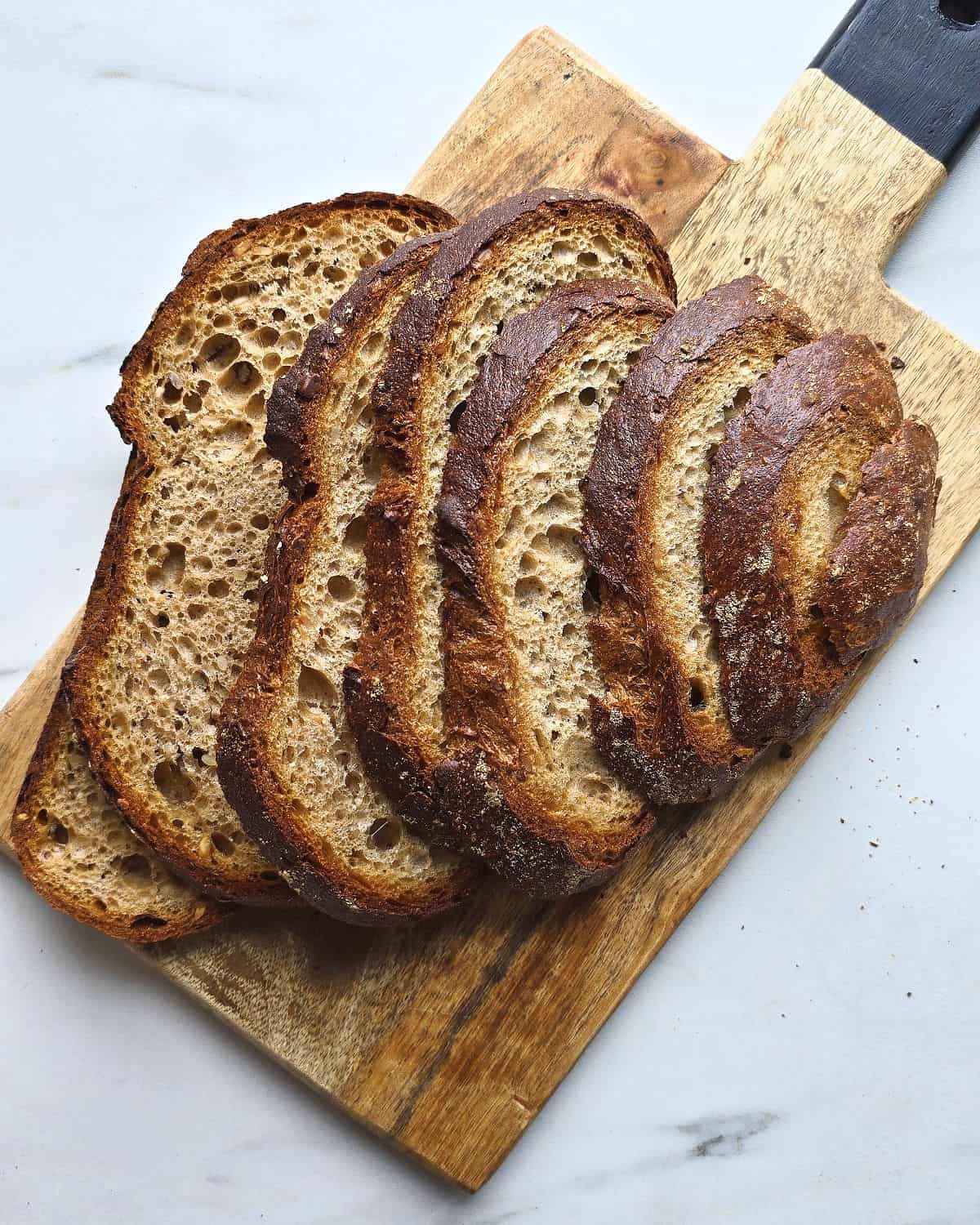 Sliced sourdough bread on a wooden board.