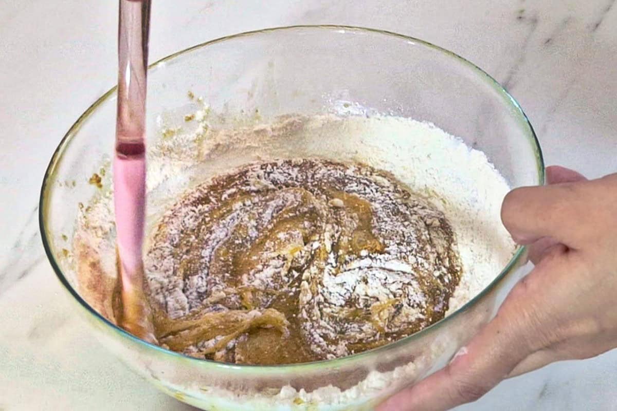 Mixing flour mix with wet batter using a spatula.