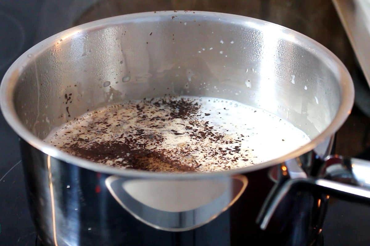 Milk and chocolate pieces together in a steel pot.