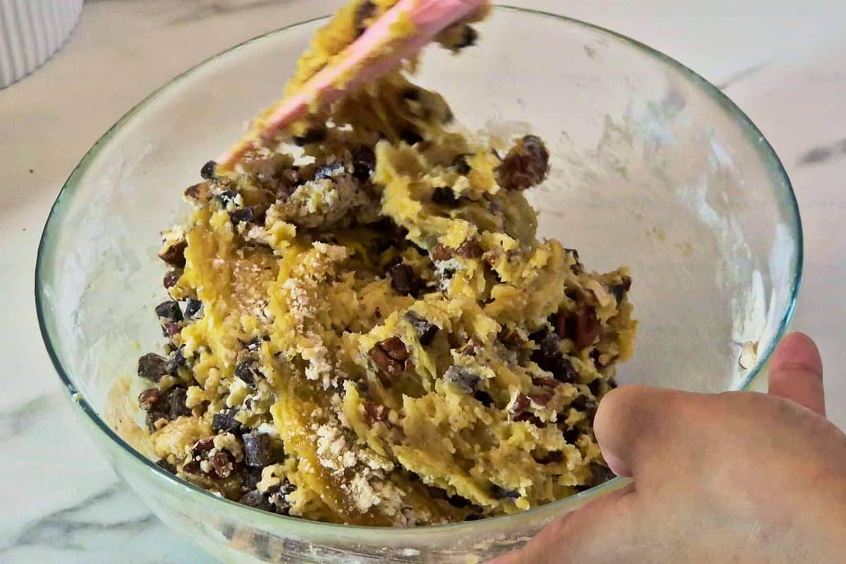 Folding chocolate chips and and pecan into cookie dough.