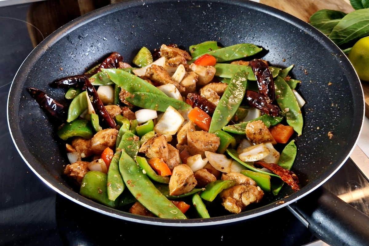 Stir frying chicken and vegetables in a wok.