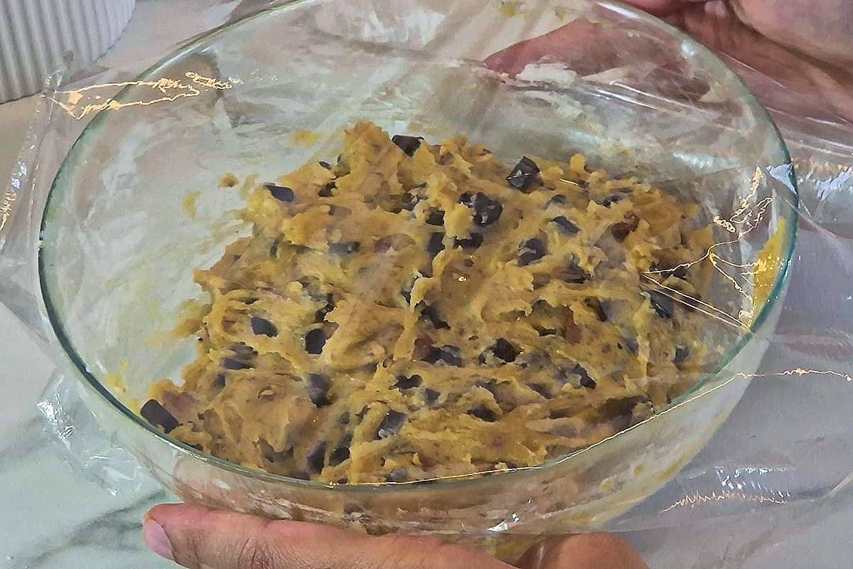 Putting cling film on a bowl of cookie dough.