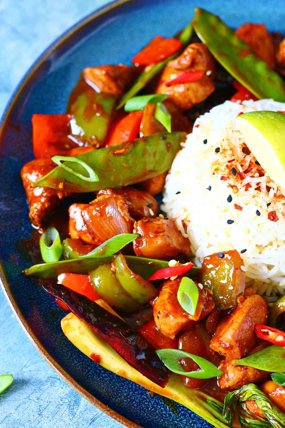 Half a plate shown with Firecracker Chicken and a mound of garnished rice.