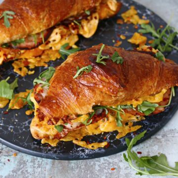 Croissant breakfast sandwich on a black marble dish.