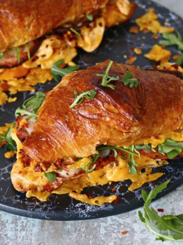 Croissant breakfast sandwich on a black marble dish.