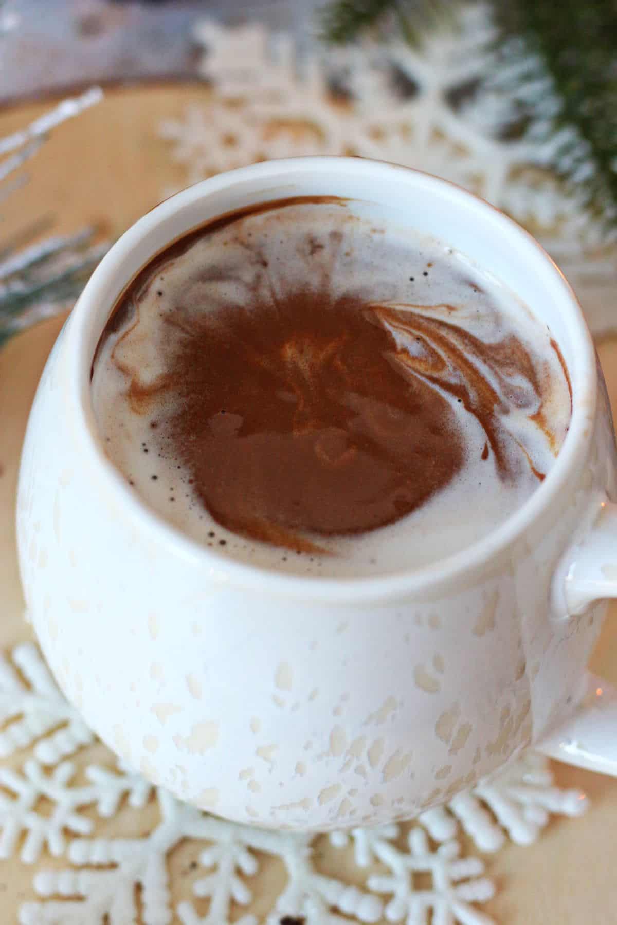 Closeup of hot chocolate in a mug swirled with whipped cream.