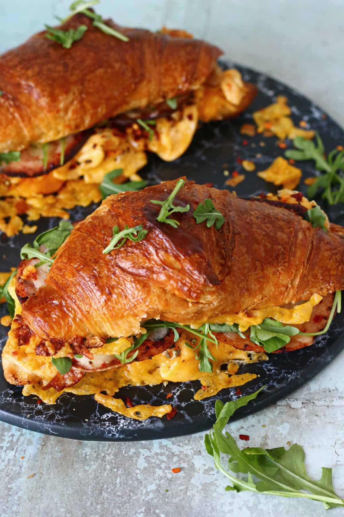 Croissant breakfast sandwich on a black marble dish.