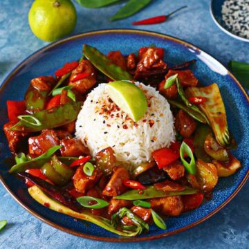 Wagamama Copycat Firecracker Chicken on a blue with a mound of rice in the middle with garnishes.