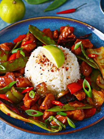 Wagamama Copycat Firecracker Chicken on a blue with a mound of rice in the middle with garnishes.